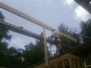 Carpenter setting a ridge beam over a new addition frame — Ice Dam Removal by Roofing Brothers in Swanton